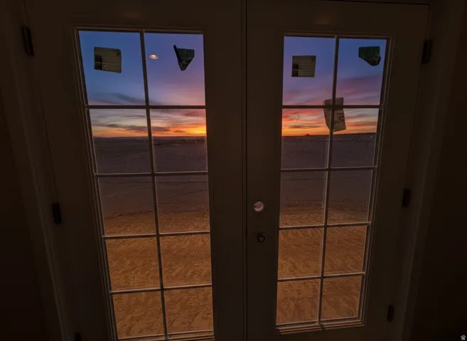 French doors with divided lites, opening to a scenic expanse under a colorful sky