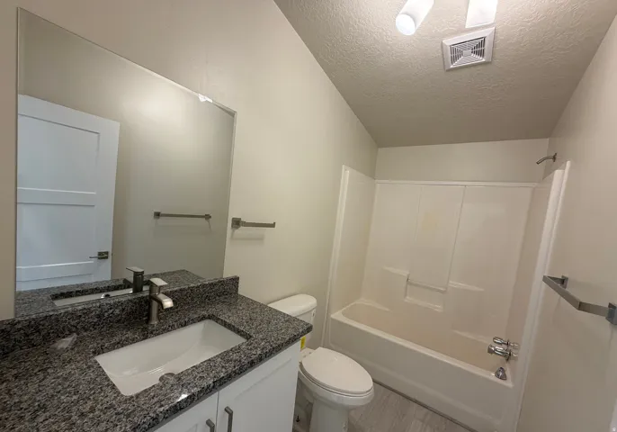 Bathroom vanity featuring a rectangular undermount sink, granite-style countertop, and chrome faucet