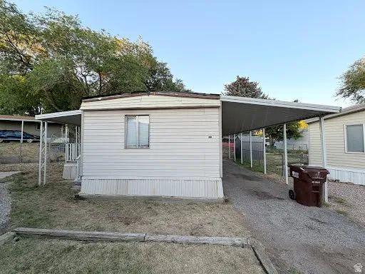 Single-story residence featuring light-colored siding and an extended carport