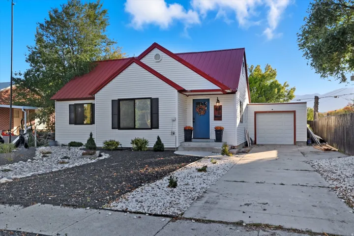 White siding exterior with a red metal roof and contrasting black shutters