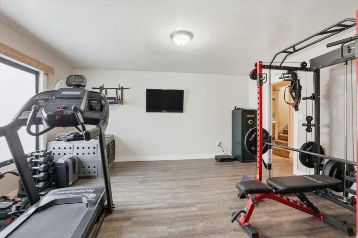 Spacious room featuring wood-finish flooring, white walls, and an overhead flush-mount light fixture