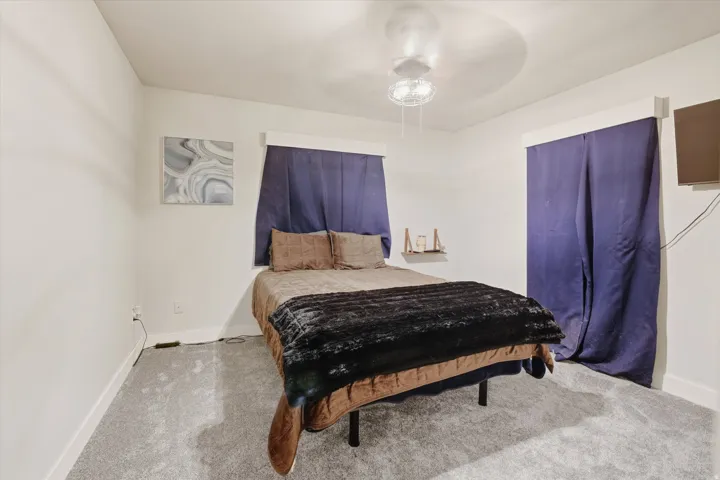 Bedroom featuring wall-to-wall carpeting, light-toned walls, and a ceiling fan with integrated lighting