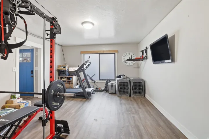 Spacious versatile room featuring wood-finish flooring, a wall-mounted flat-screen display, and a large window providing ambient light