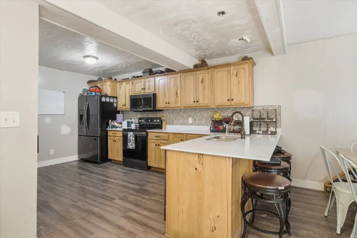 Kitchen featuring wood-finish flooring, natural wood cabinetry, light-toned countertops, and a tile backsplash