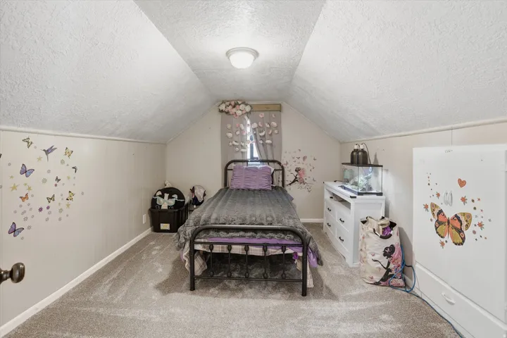 Carpeted room featuring sloped ceilings, a single window, and a flush mount light fixture