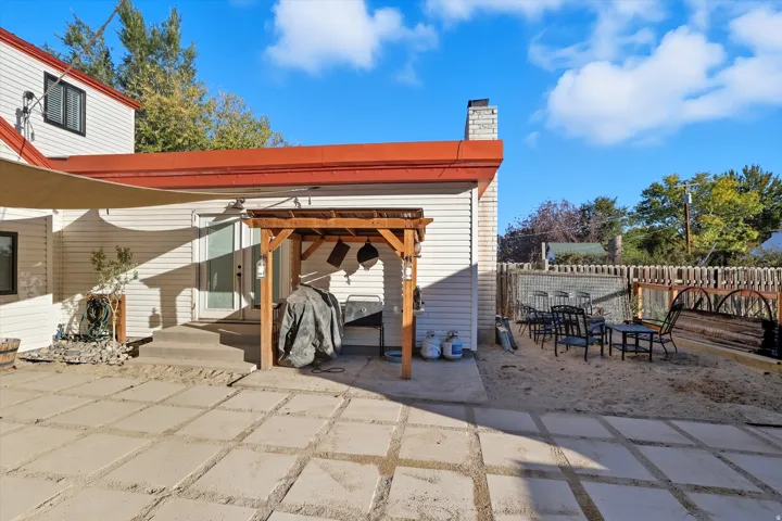 Exterior patio area featuring concrete paver flooring, a wooden pergola, and white siding