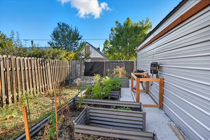 Backyard featuring multiple raised garden beds, a concrete pathway, and a wooden privacy fence
