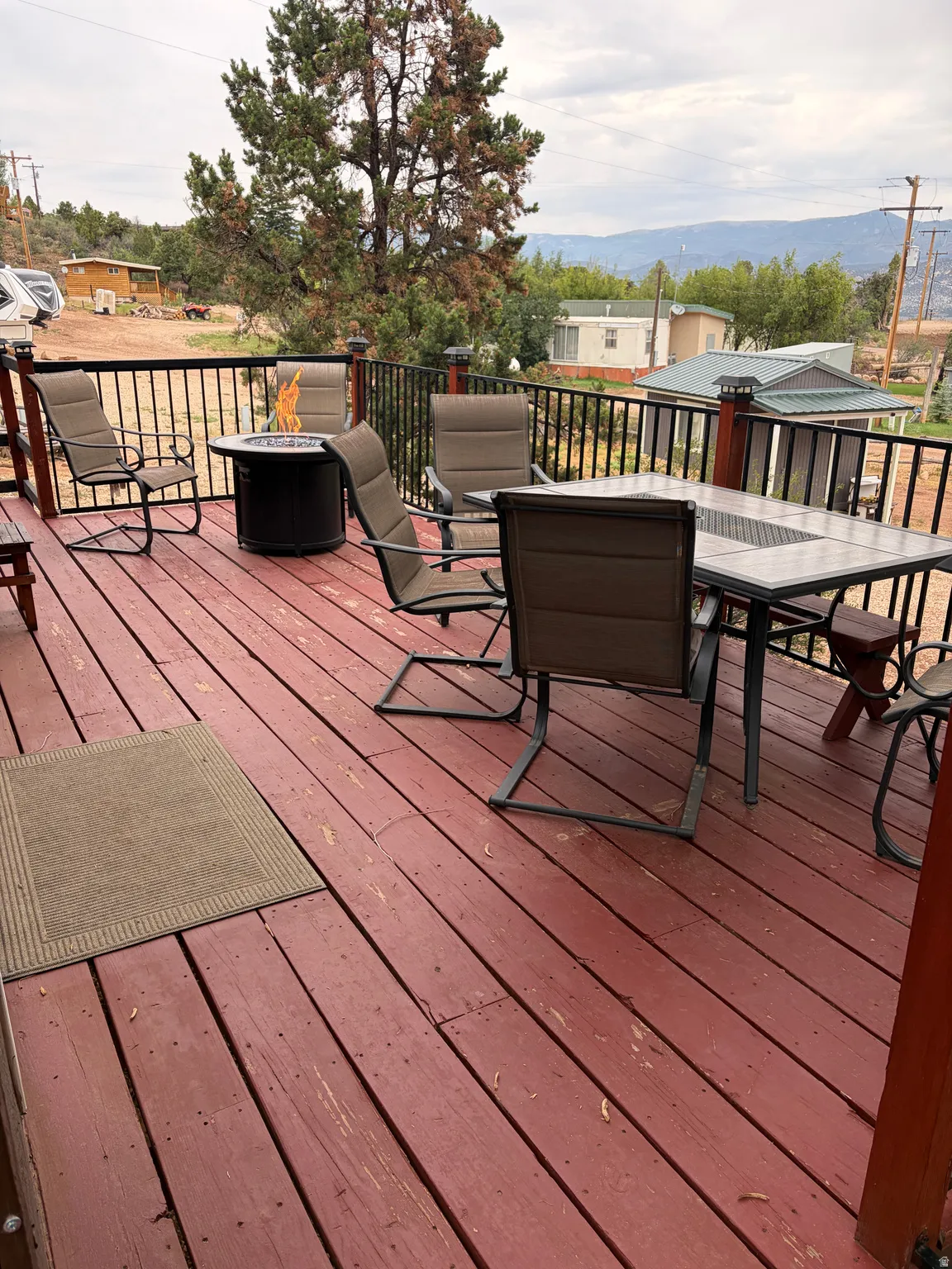 Expansive red-stained wooden deck featuring black metal railings and a built-in fire pit