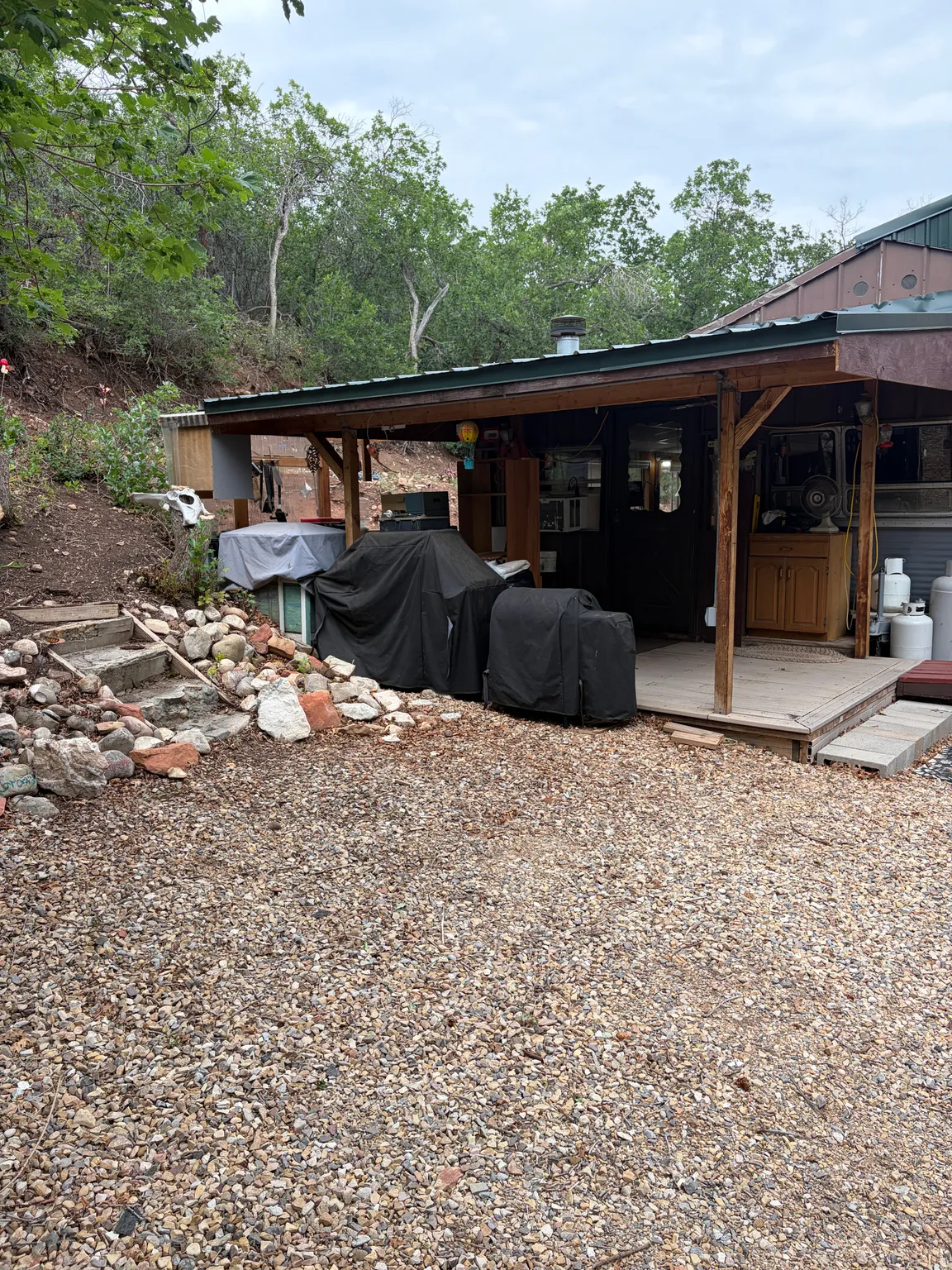 Exterior wood-frame covered patio with a gravel ground surface