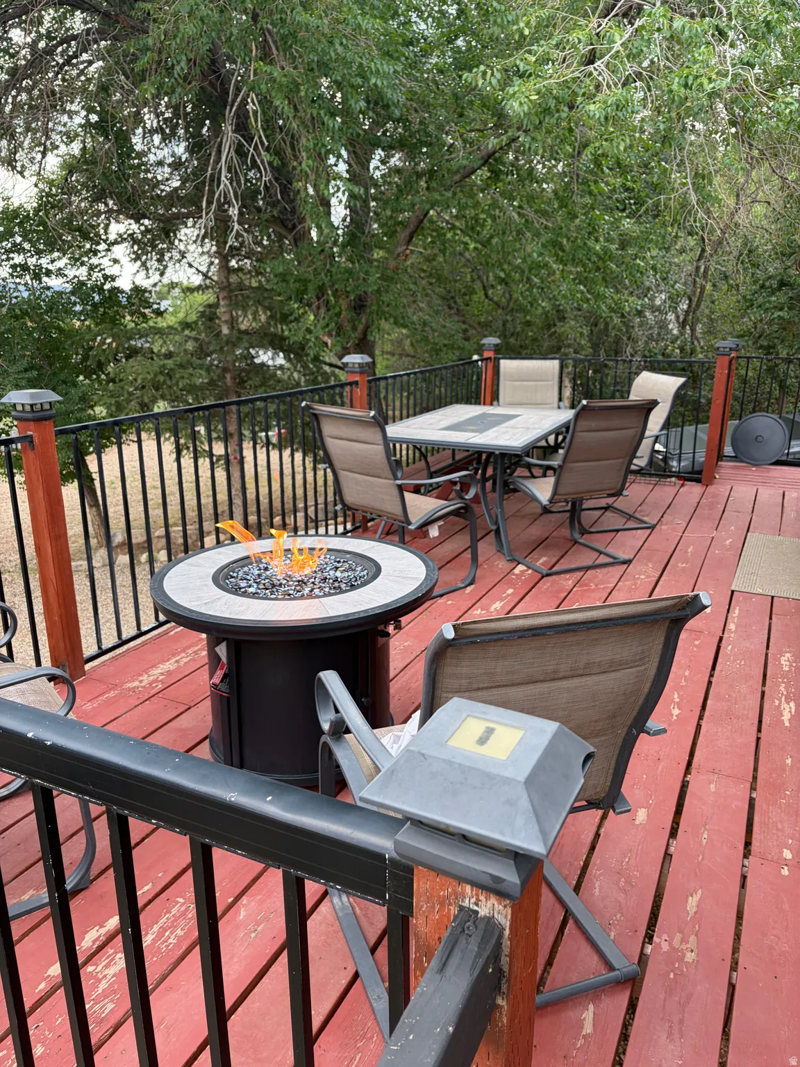 Expansive red-stained deck featuring a black metal railing system with wood posts and solar post caps