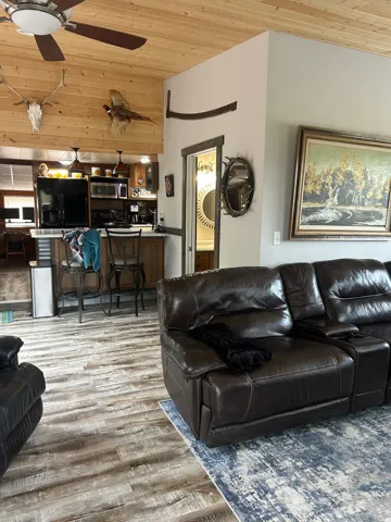 Expansive living area featuring wood-finish flooring and a wood-paneled ceiling with a ceiling fan