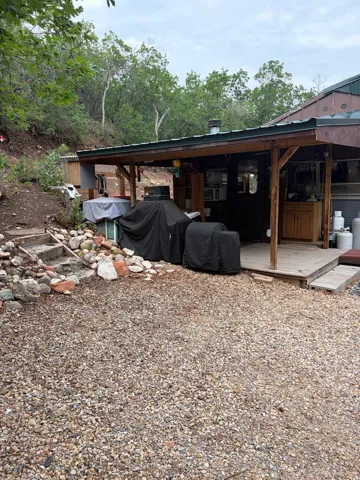 Exterior wood-frame covered patio with a gravel ground surface