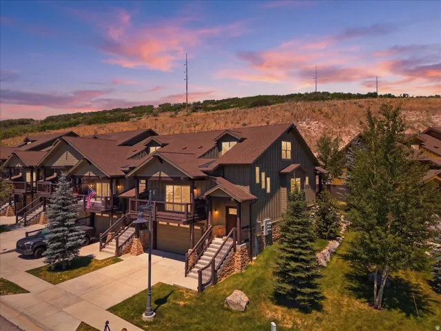 Townhome featuring a brown roof, dark green siding, and stone accents