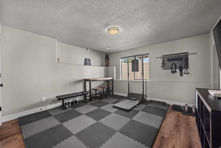 Multipurpose room featuring checkerboard puzzle mat flooring, light gray walls, a built-in window, and wood-finish flooring portions
