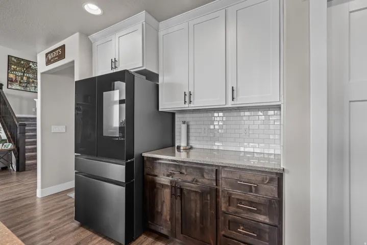 Kitchen area with a built-in refrigerator, white upper cabinetry, and dark wood-finish lower cabinetry