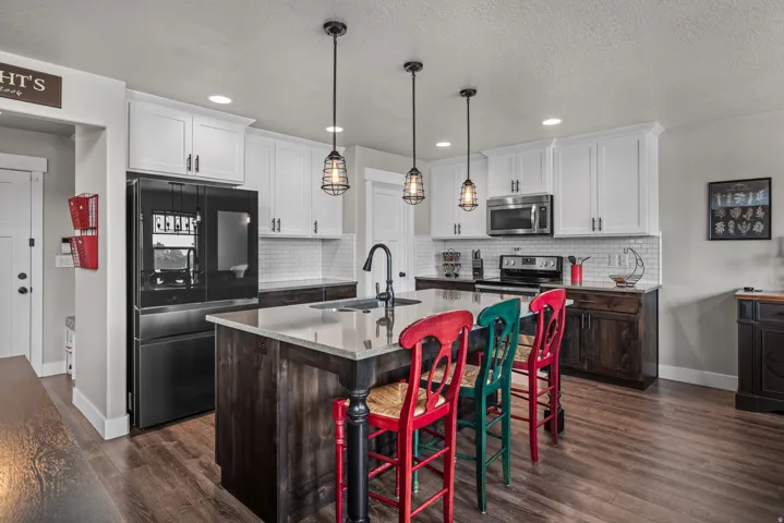Kitchen featuring wood-finish flooring, white upper cabinetry, dark lower cabinetry, and a subway tile backsplash