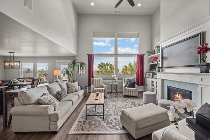 Open-concept living area with soaring ceilings, wood-finish flooring, a contemporary fireplace with a tiled surround, and extensive windowing
