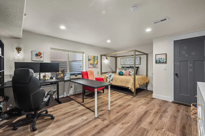 Open-concept room featuring wood-finish flooring, recessed lighting, and a dark-paneled door with white trim