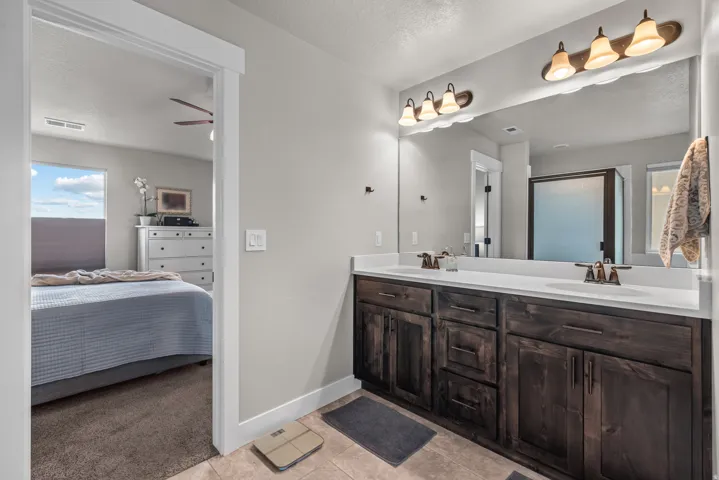Dual vanity with dark wood-finish cabinetry, white countertops, and bronze-tone fixtures