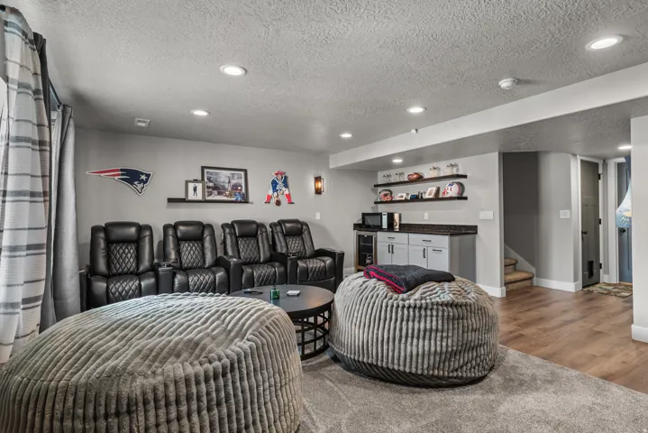 Entertainment space featuring recessed lighting, a built-in wet bar with cabinetry and solid surface countertop, wood-finish flooring, and a carpeted area