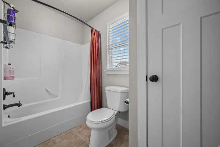 Bathroom featuring a combination shower and tub, tile flooring, and a window with blinds