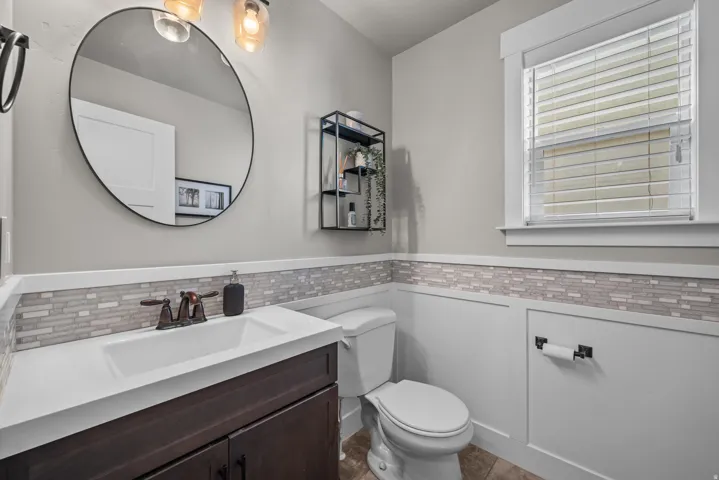 Bathroom featuring a dark wood-finish vanity with an integrated sink, white countertop, and mosaic tile backsplash