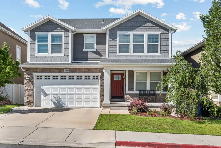 Two-story residence featuring a striking red entry door, an integrated two-car garage, and a covered porch