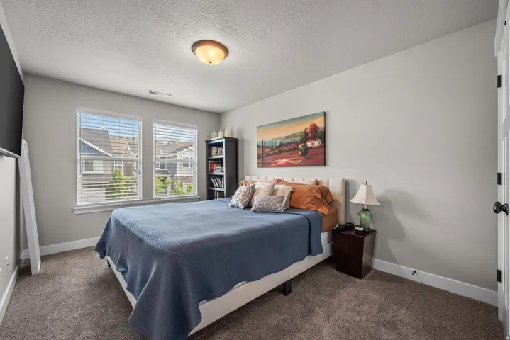 Spacious room featuring neutral paint, two windows with blinds, and durable carpeting
