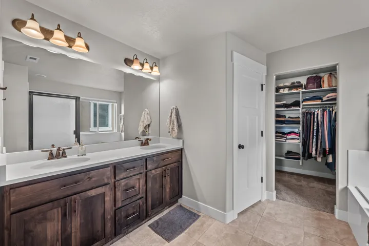 Spacious bathroom featuring a dual vanity with dark wood cabinetry and white countertops