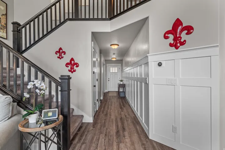 Entryway featuring wood-finish flooring, a white board and batten accent wall, and a dark wood staircase with matching railings