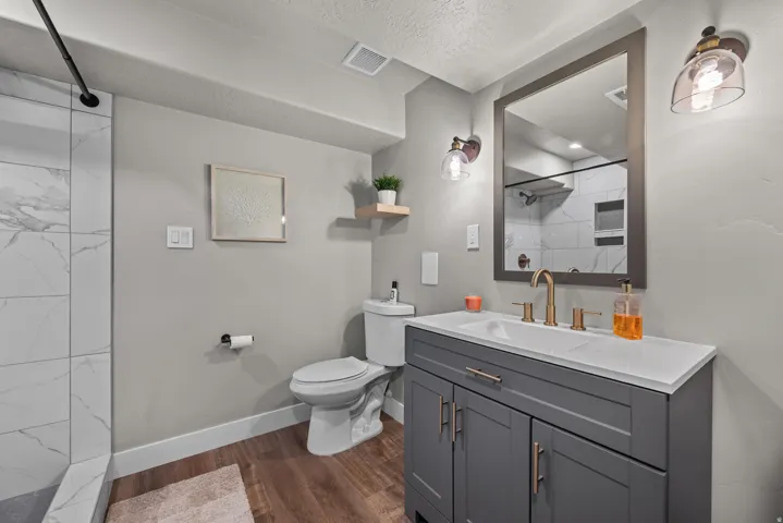 Contemporary bathroom featuring a grey vanity with a white countertop, gold-finish faucet, and coordinating hardware