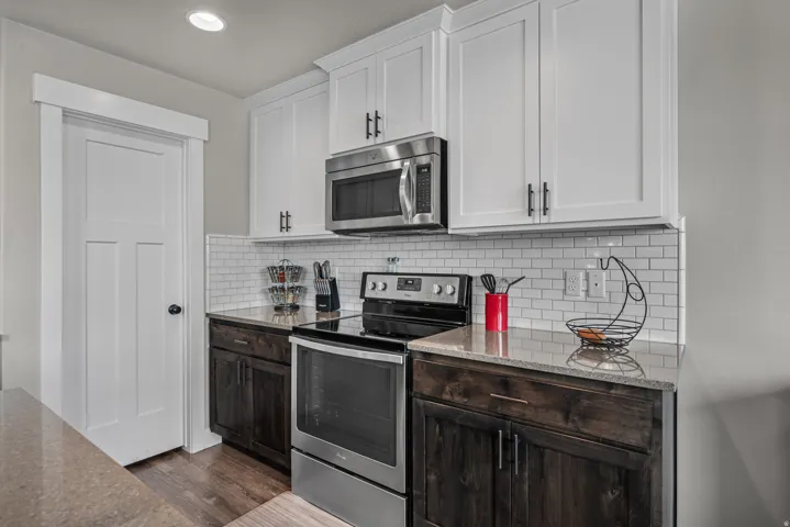 Kitchen featuring white shaker-style upper cabinetry, dark wood-finish lower cabinetry, and stainless steel appliances