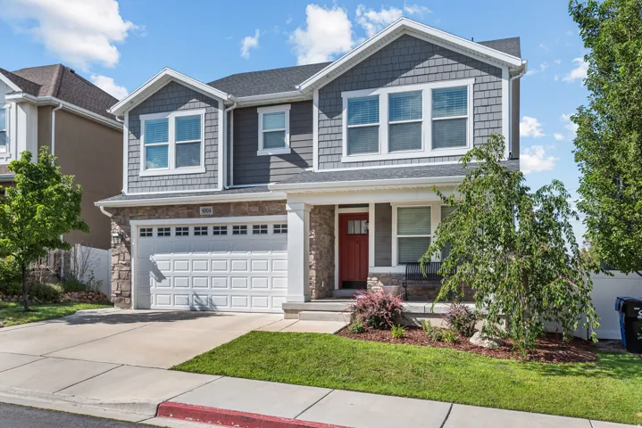 Contemporary two-story exterior featuring gray siding, stone accents, a red front door, an attached two-car garage, and a concrete driveway