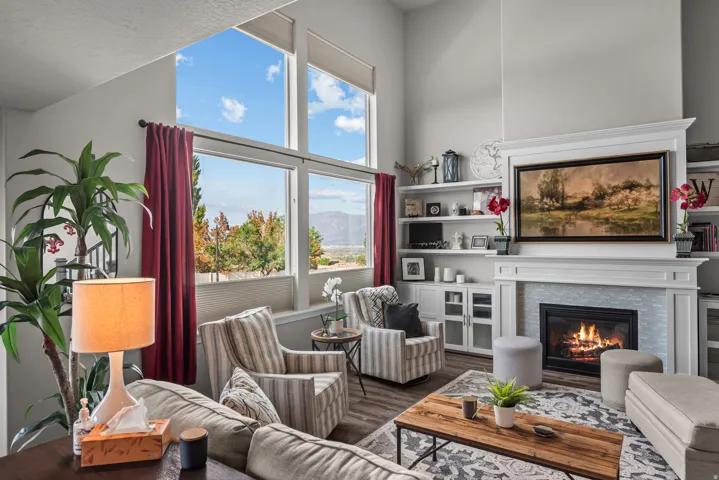 Spacious living area featuring large windows, vaulted ceilings, built-in shelving, a fireplace with a tile surround, and wood-finish flooring
