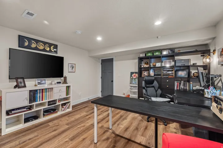 Versatile room featuring wood-finish flooring, recessed lighting, and a built-in shelving unit