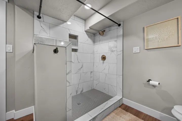 Contemporary shower featuring large format white tile with gray veining, a hexagonal tile floor, and a built-in shower niche