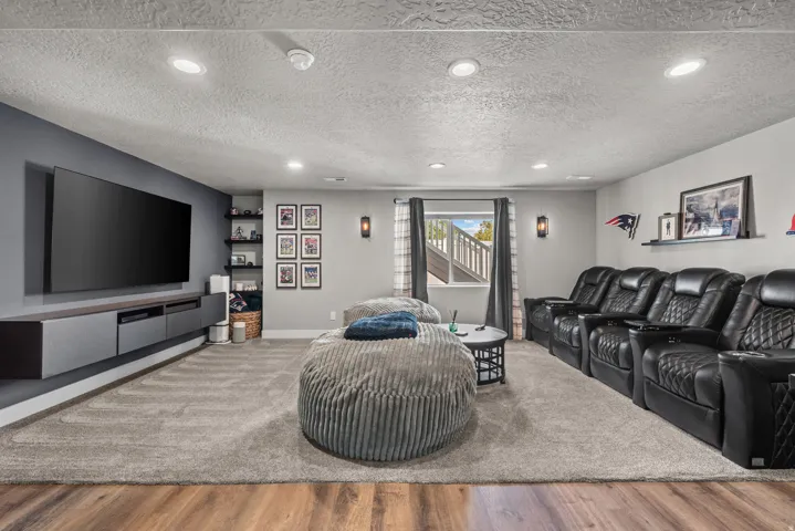 Spacious entertainment area featuring wood-finish flooring, recessed lighting, and a large window providing natural illumination