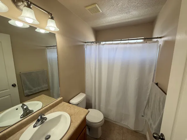 Bathroom featuring a single vanity with an oval sink, a light-toned countertop, and a brushed nickel faucet