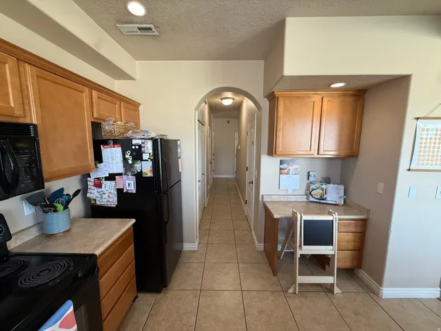 Spacious kitchen featuring warm wood cabinetry, light-toned countertops, and tile flooring