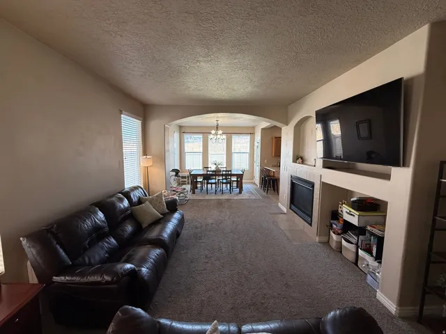 Open-concept living space featuring a built-in entertainment center, fireplace with tile surround, and carpet flooring