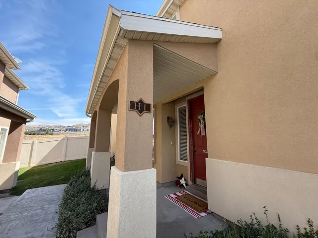 Stucco exterior with a covered porch featuring arched columns and a red entry door