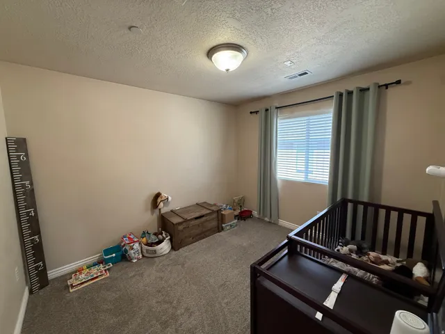 Carpeted room with neutral wall tones and a single window featuring horizontal blinds