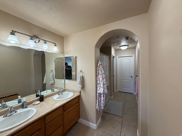 Dual vanity with undermount sinks and laminate countertops, complemented by a large mirror and brushed nickel four-light fixture