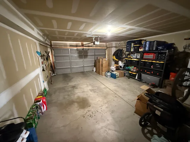 Attached garage featuring a concrete floor, overhead lighting, and a paneled garage door
