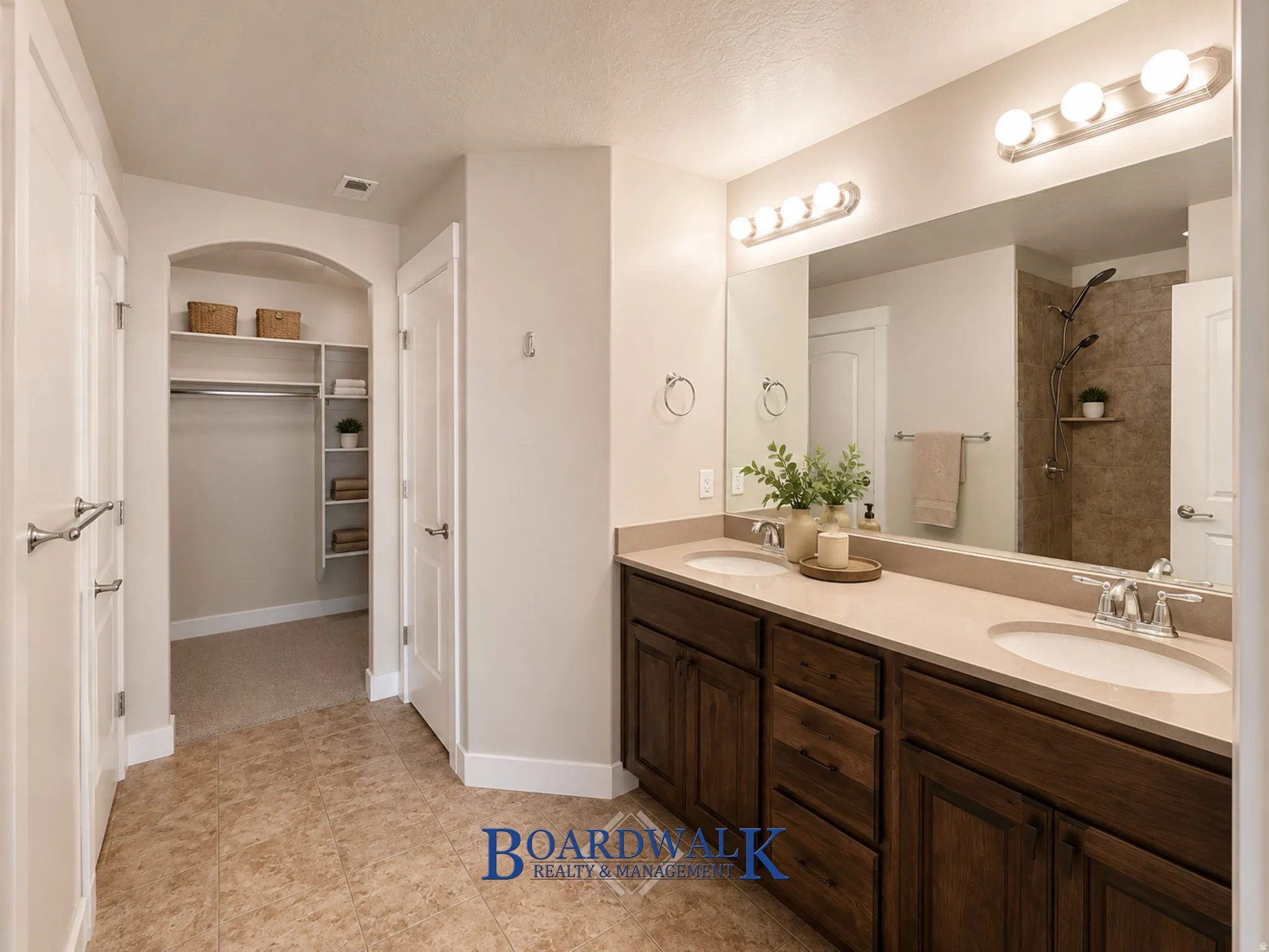 Dual basin vanity with undermount sinks, warm wood cabinetry, and a large wall-mounted mirror with overhead lighting