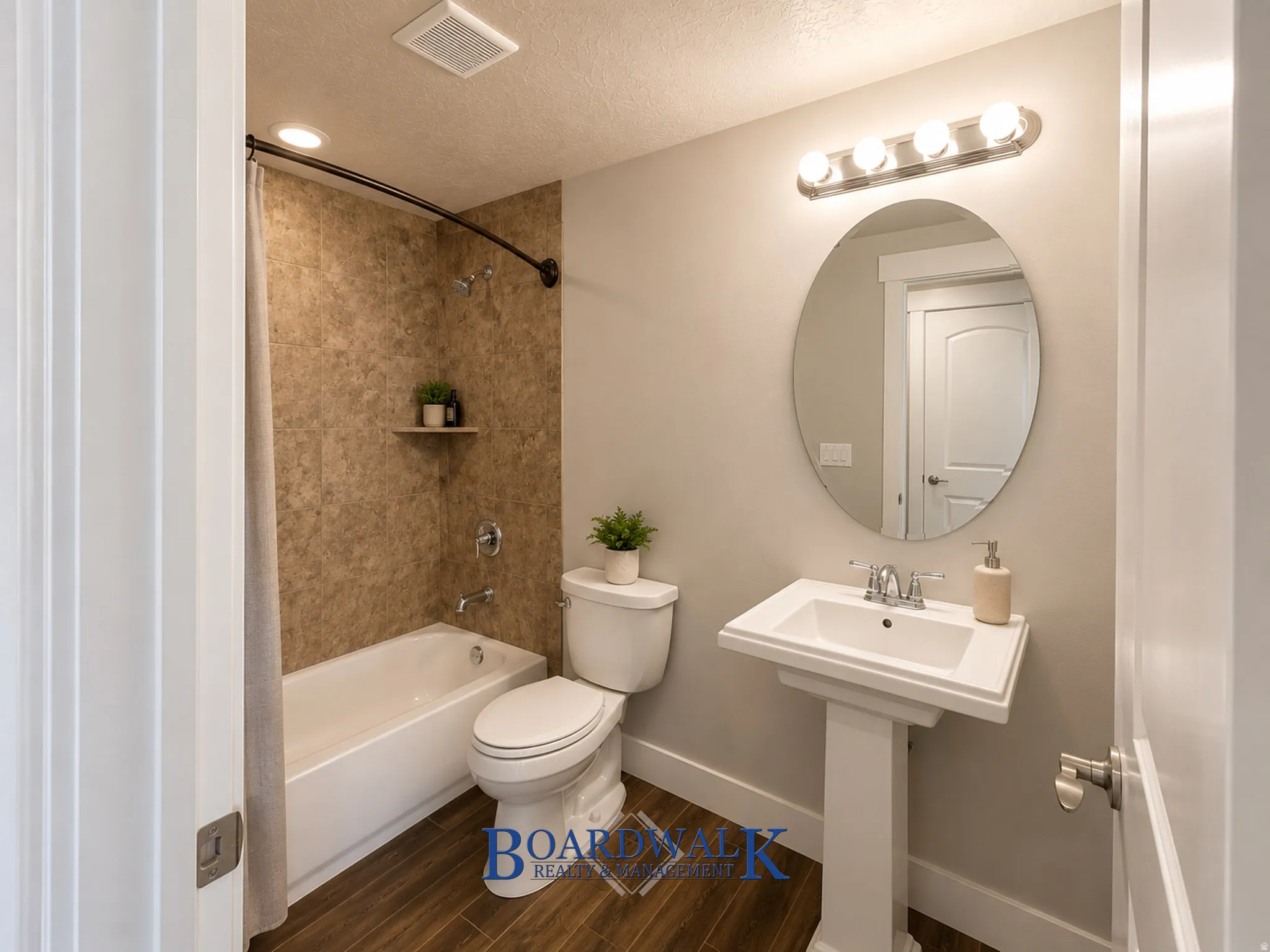Pedestal sink with an oval mirror and brushed nickel vanity light
