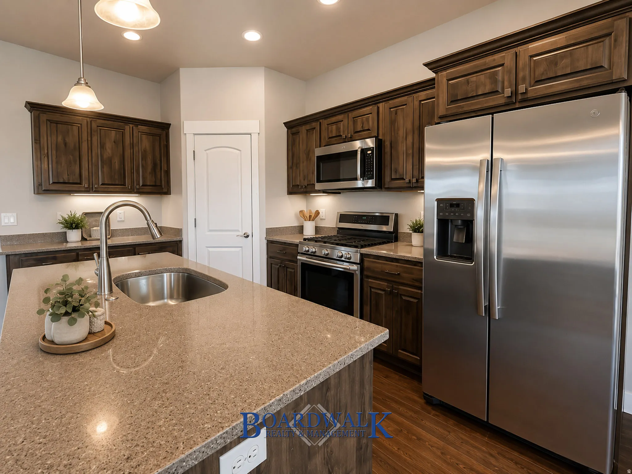 Kitchen featuring wood-finish cabinetry, stainless steel appliances, and a central island with an undermount sink and gooseneck faucet