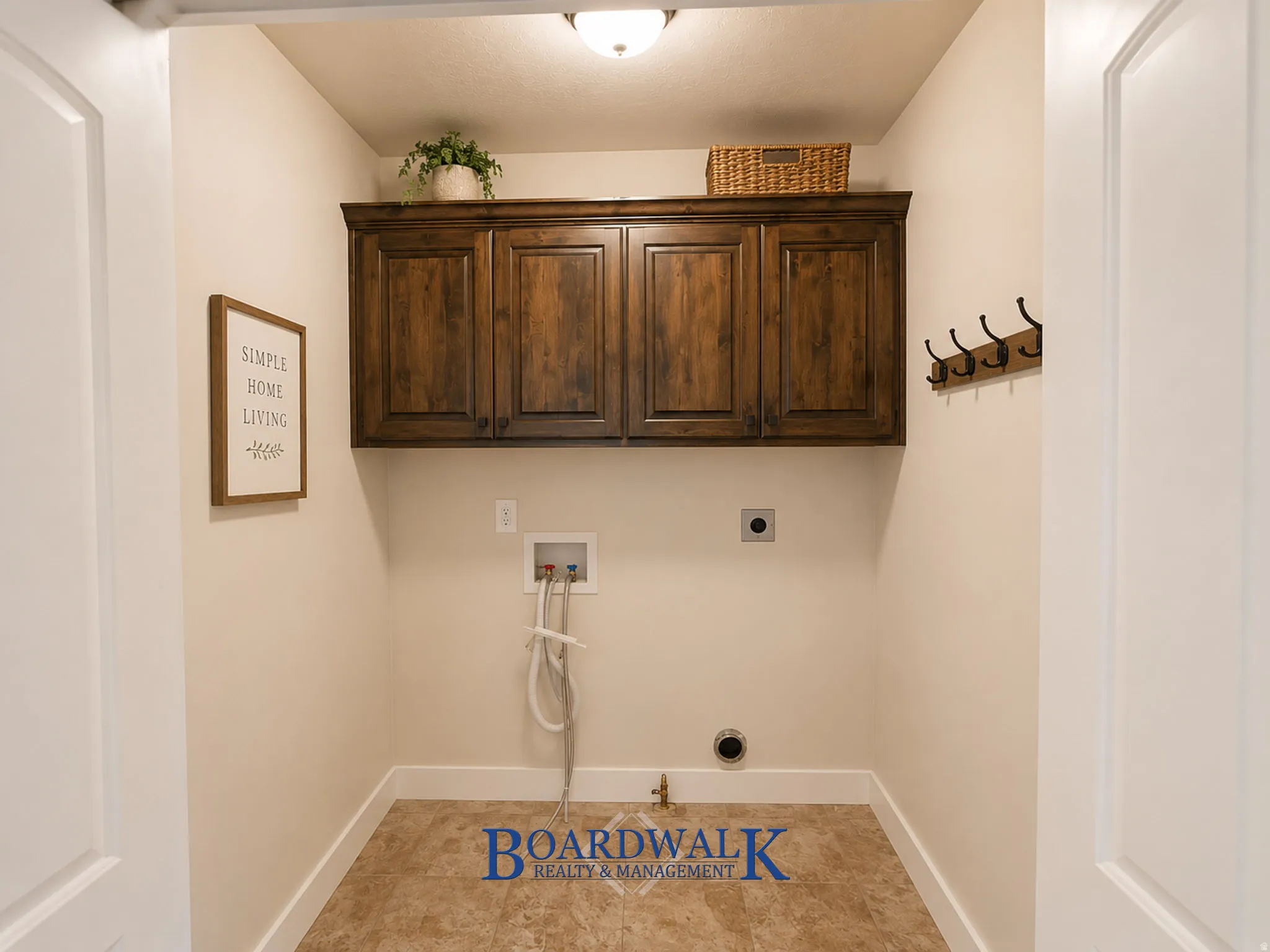 Dedicated utility space featuring overhead wood cabinetry and tile flooring
