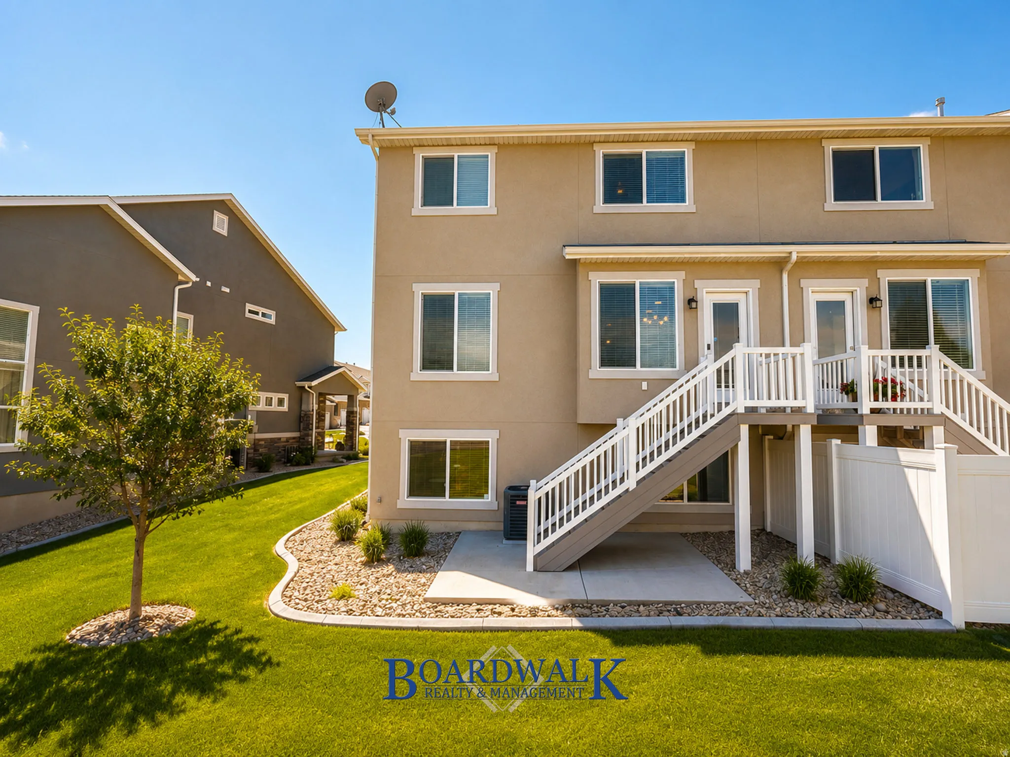 Exterior featuring a two-story design with light stucco siding, multiple windows, and two outdoor staircases with white railings