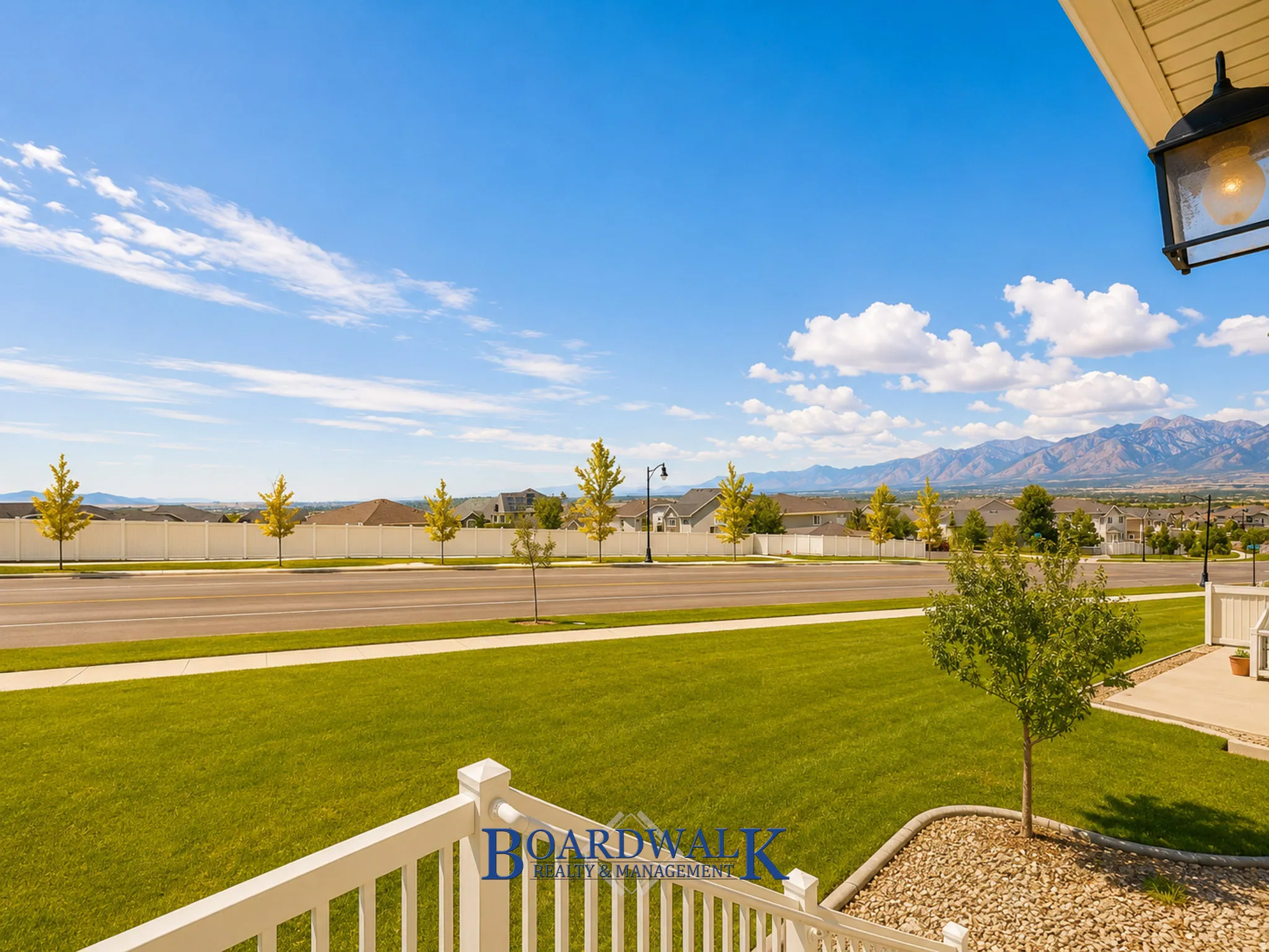 Expansive front lawn with a manicured green space, complemented by a white railing porch